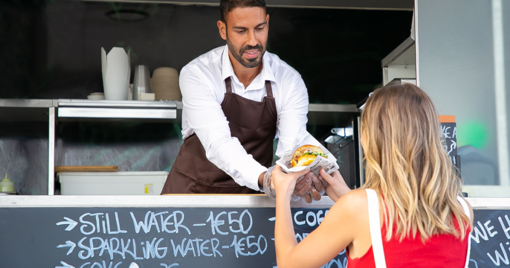 food truck owner using ai accounting software for food trucks on smartphone between service rushes